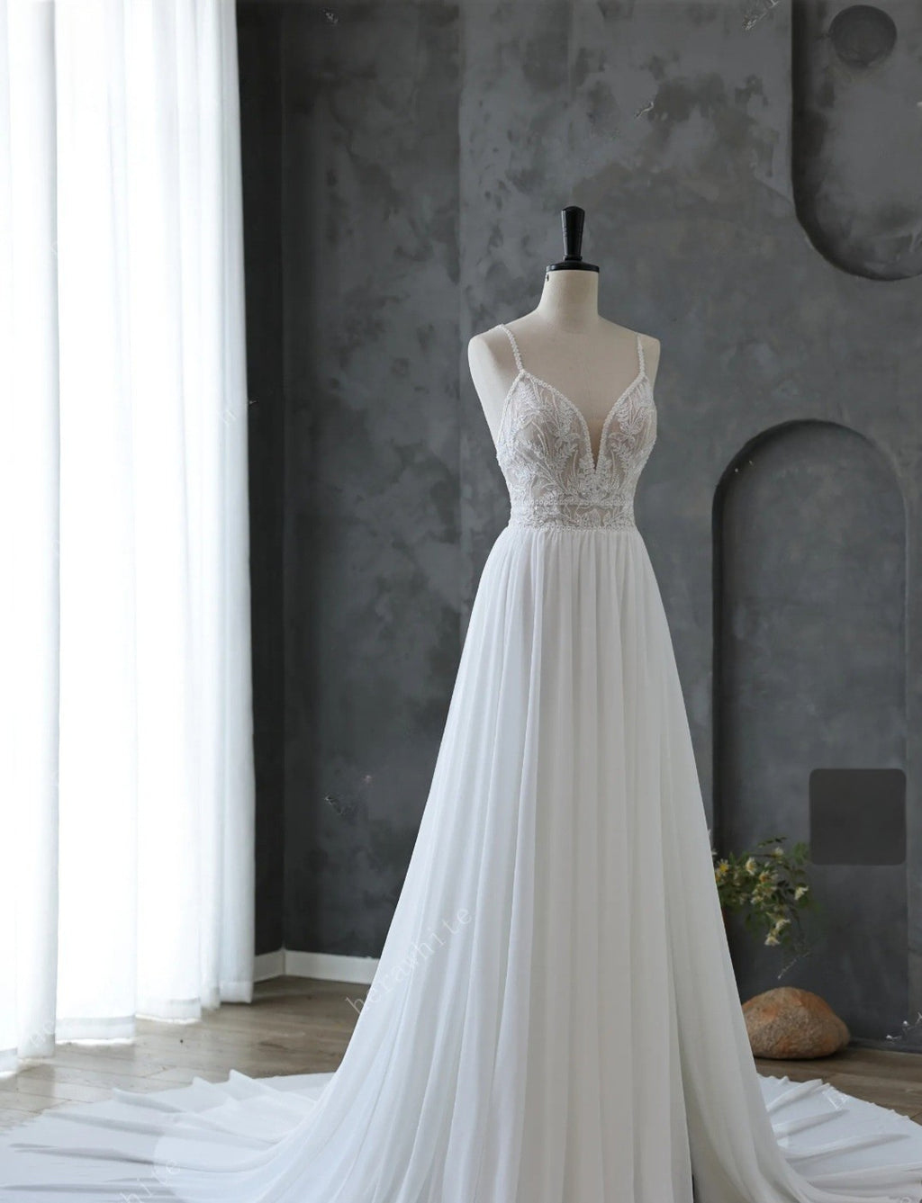 White wedding dress on a mannequin against a gray wall.