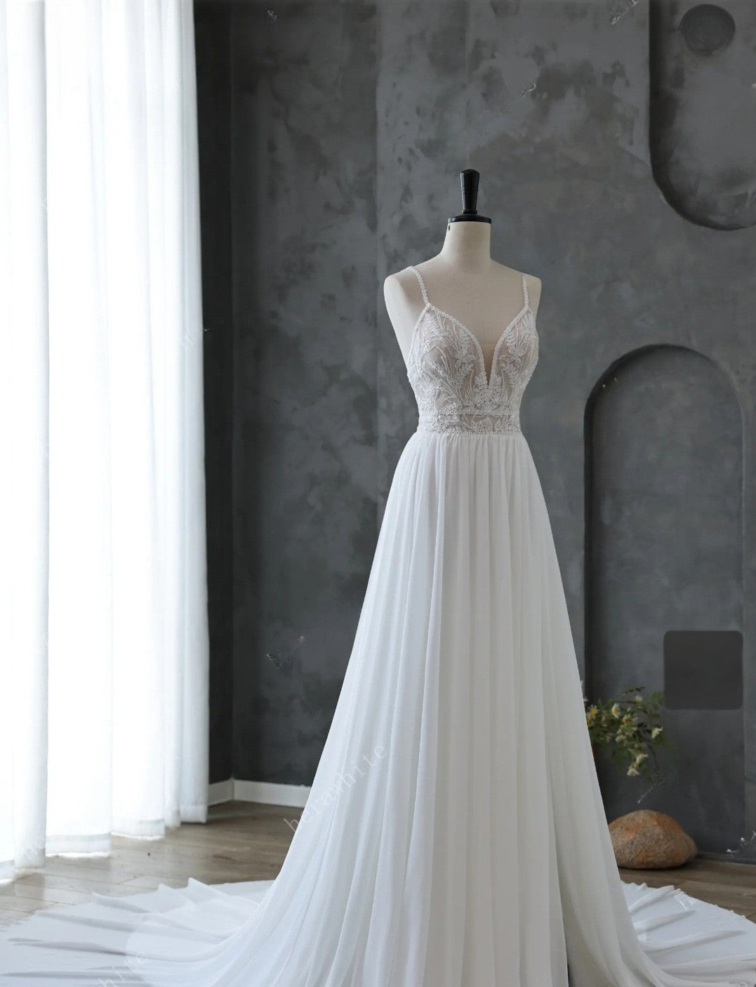 White wedding dress on a mannequin against a gray wall.