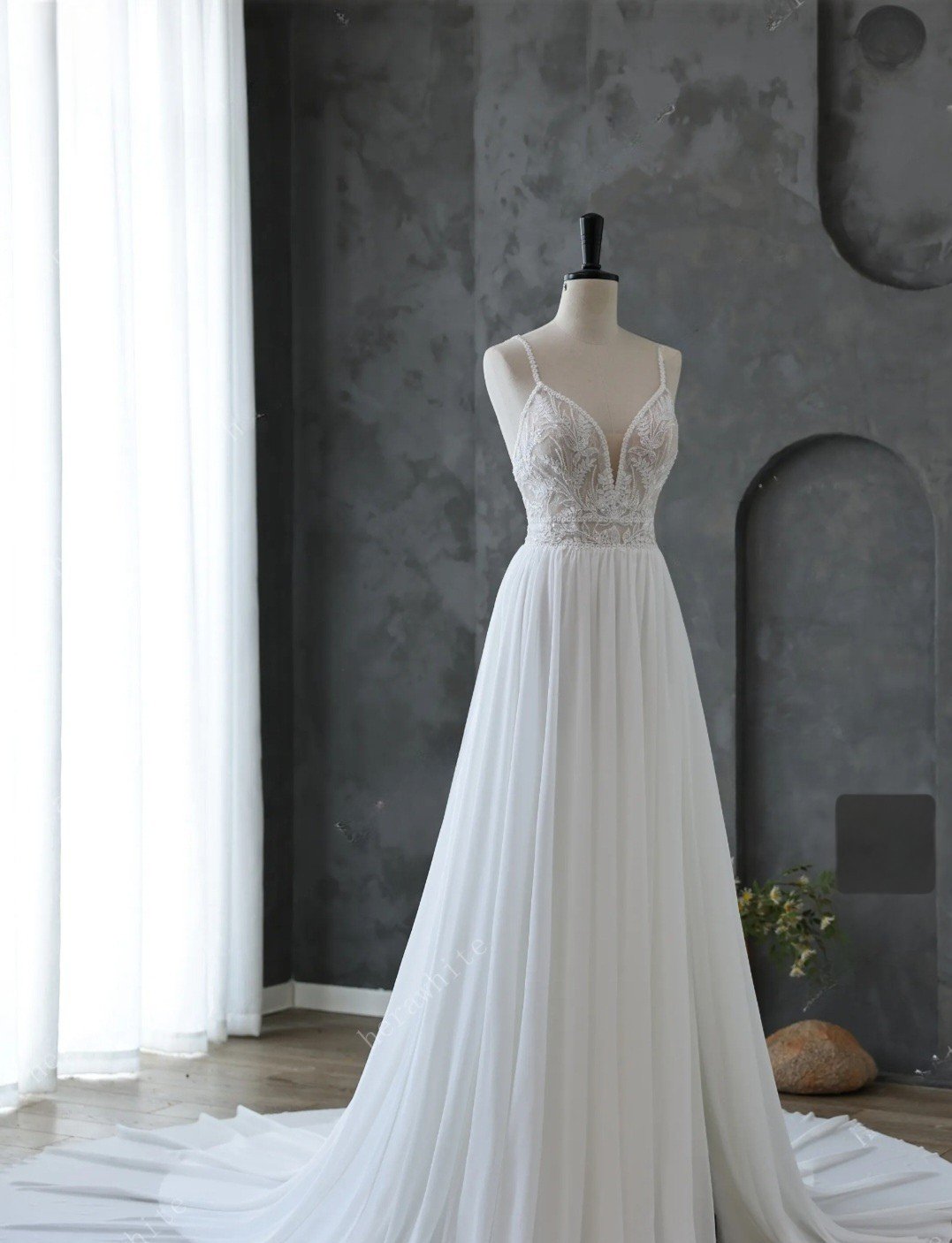 White wedding dress on a mannequin against a gray wall.