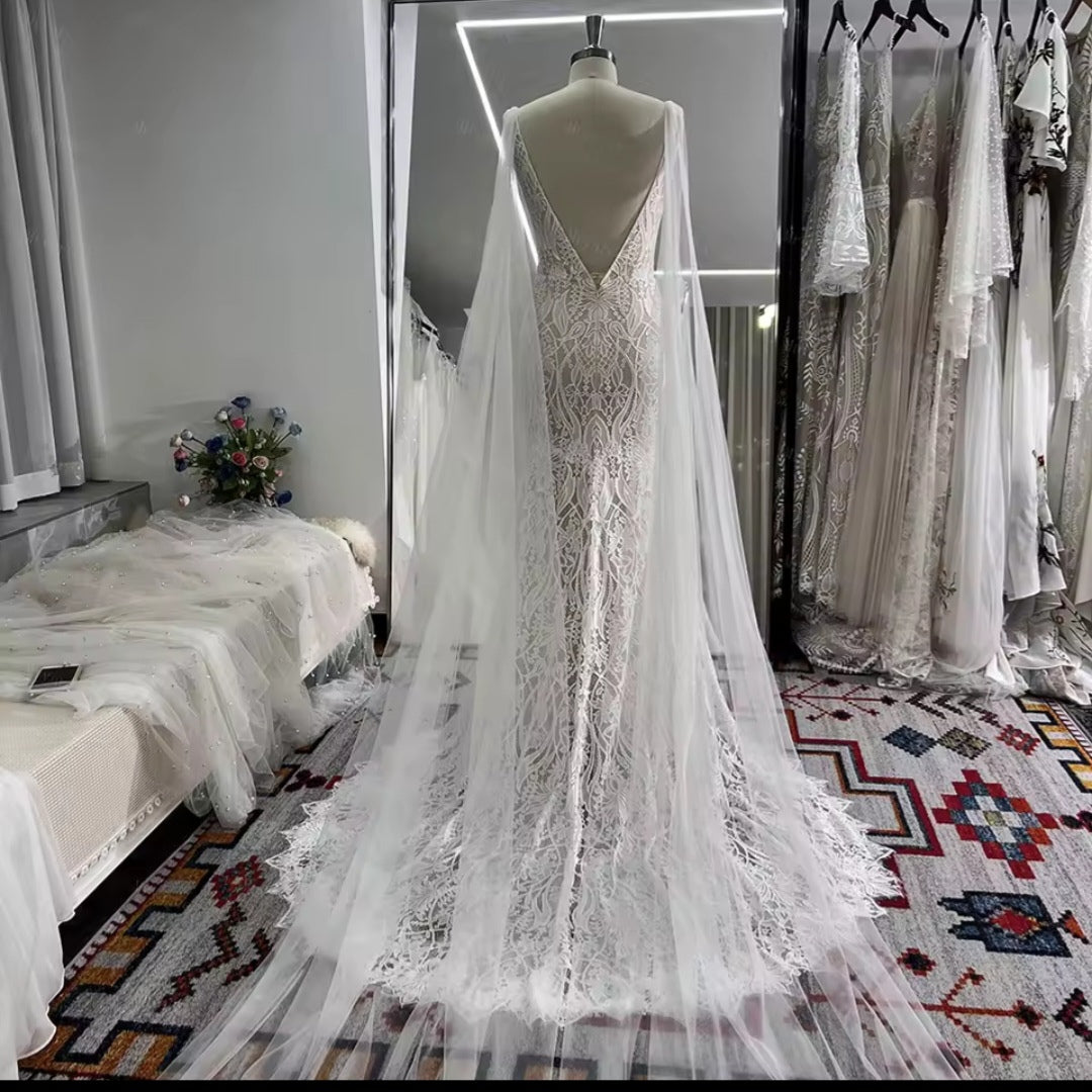 Elegant white lace wedding dress on a mannequin in a room with other dresses and decor.
