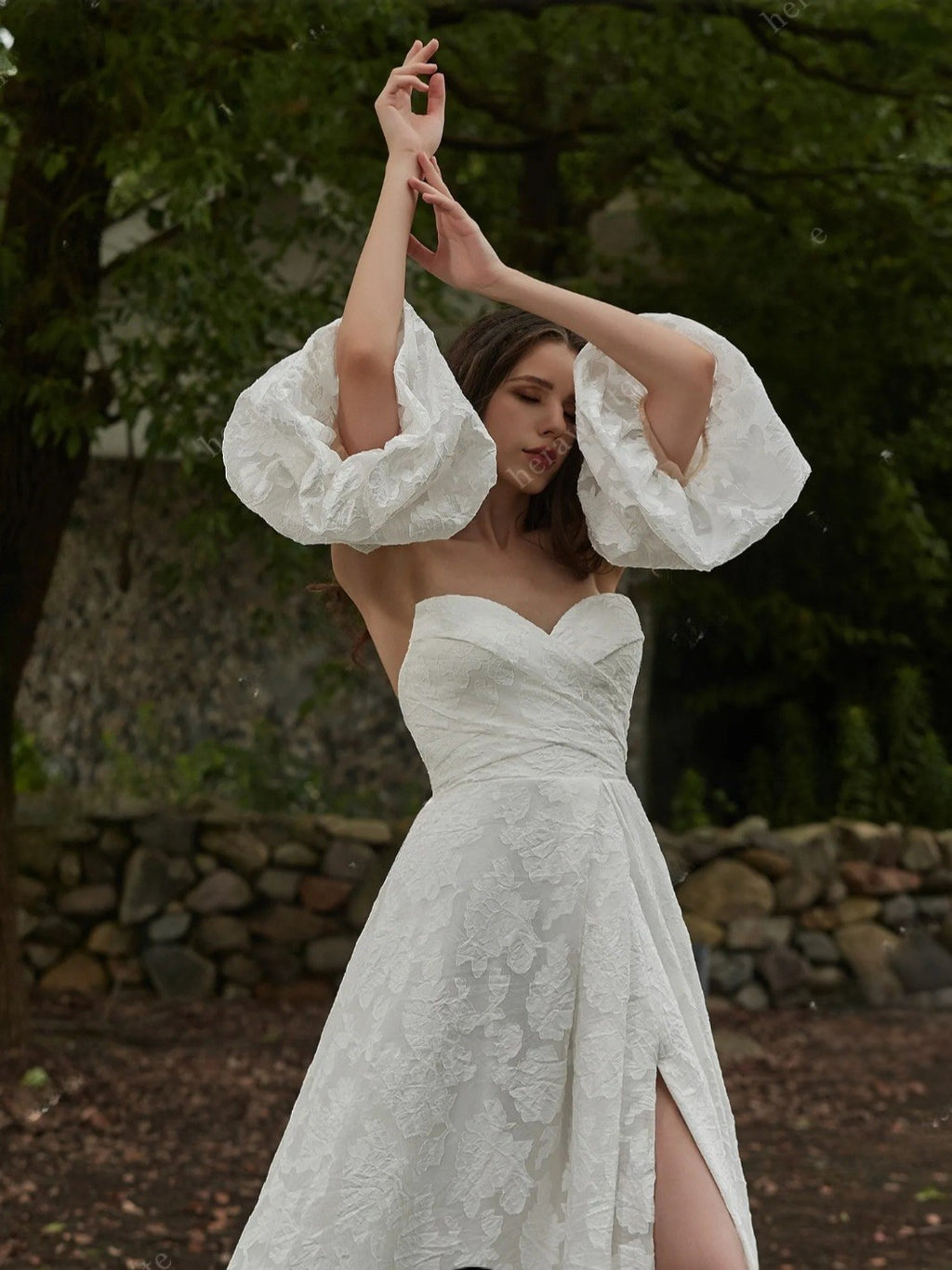Woman in a white lace dress with puffed sleeves standing outdoors.