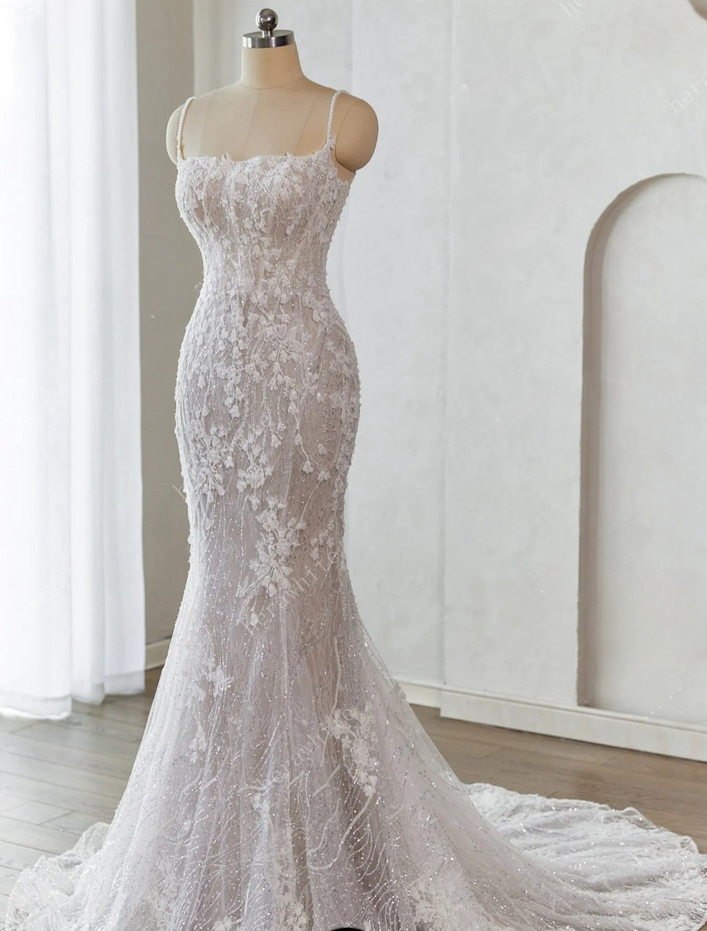 Elegant white lace wedding dress on a mannequin against a neutral background