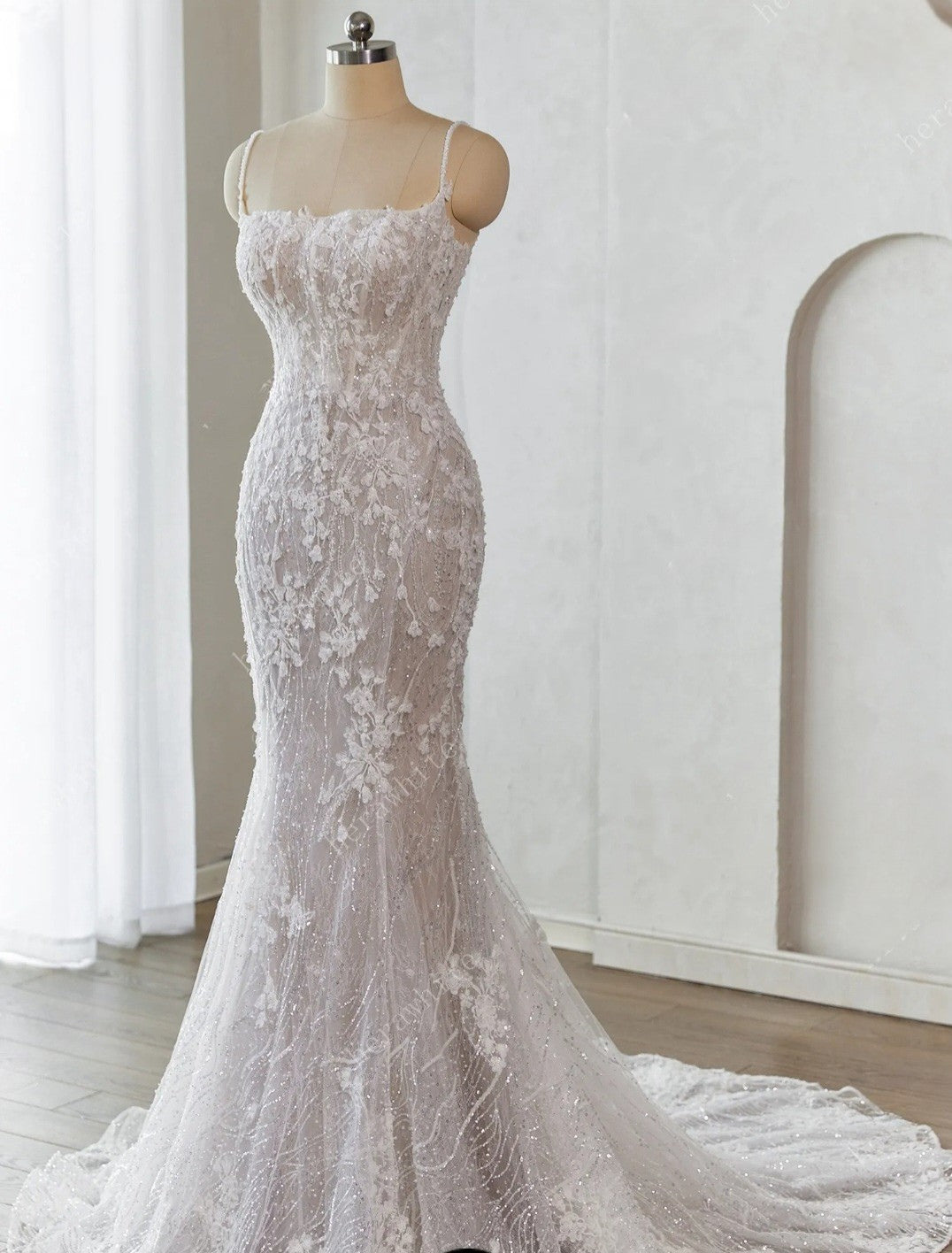 Elegant white lace wedding dress on a mannequin against a neutral background