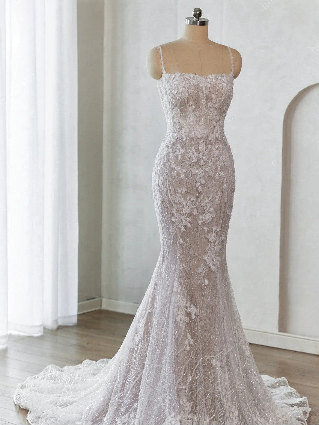 White lace mermaid gown on a mannequin against a white background