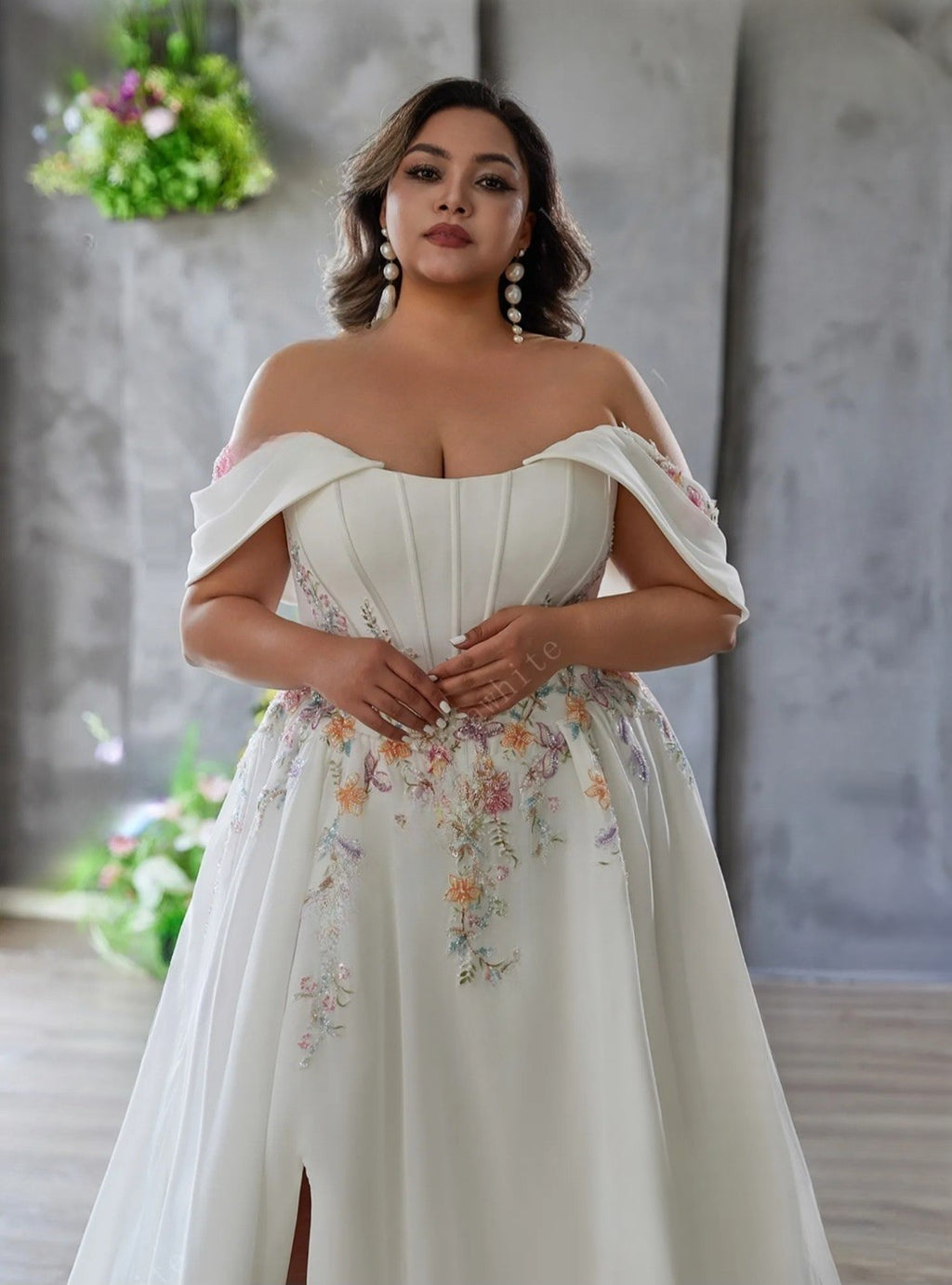 Woman wearing a white off-shoulder dress with floral patterns against a neutral background