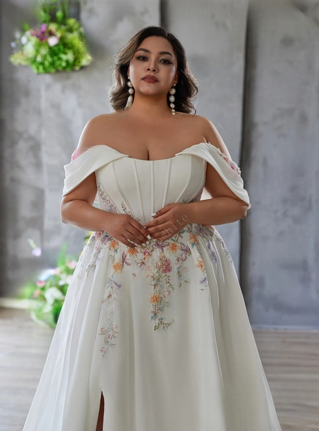 Woman wearing a white off-shoulder dress with floral patterns against a neutral background