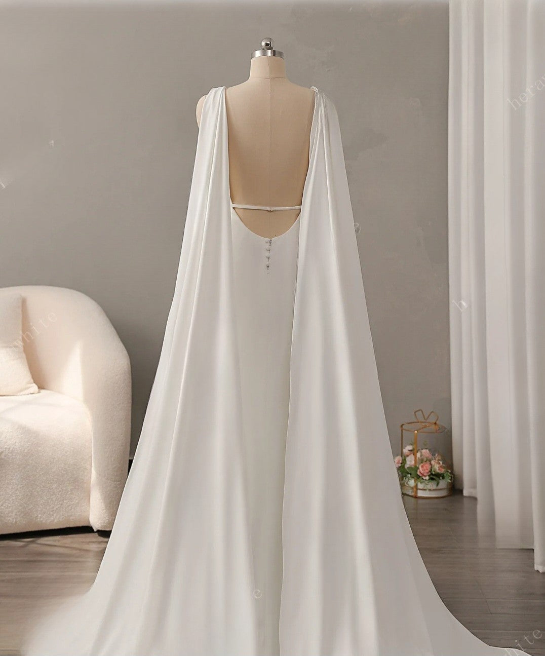 White wedding dress with cape on a mannequin against a neutral background
