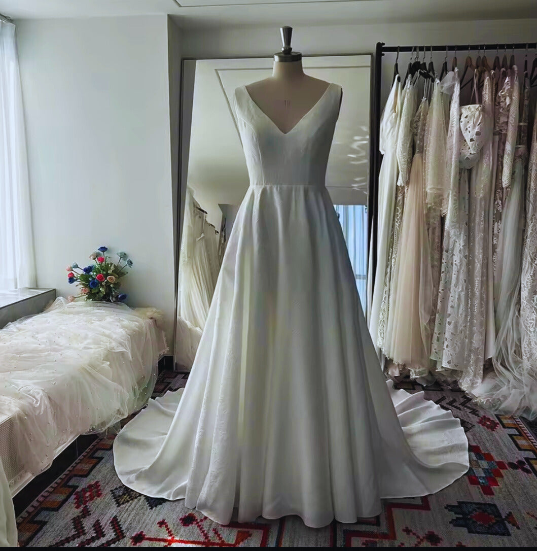 White wedding dress on a mannequin in a room with other dresses and decor.