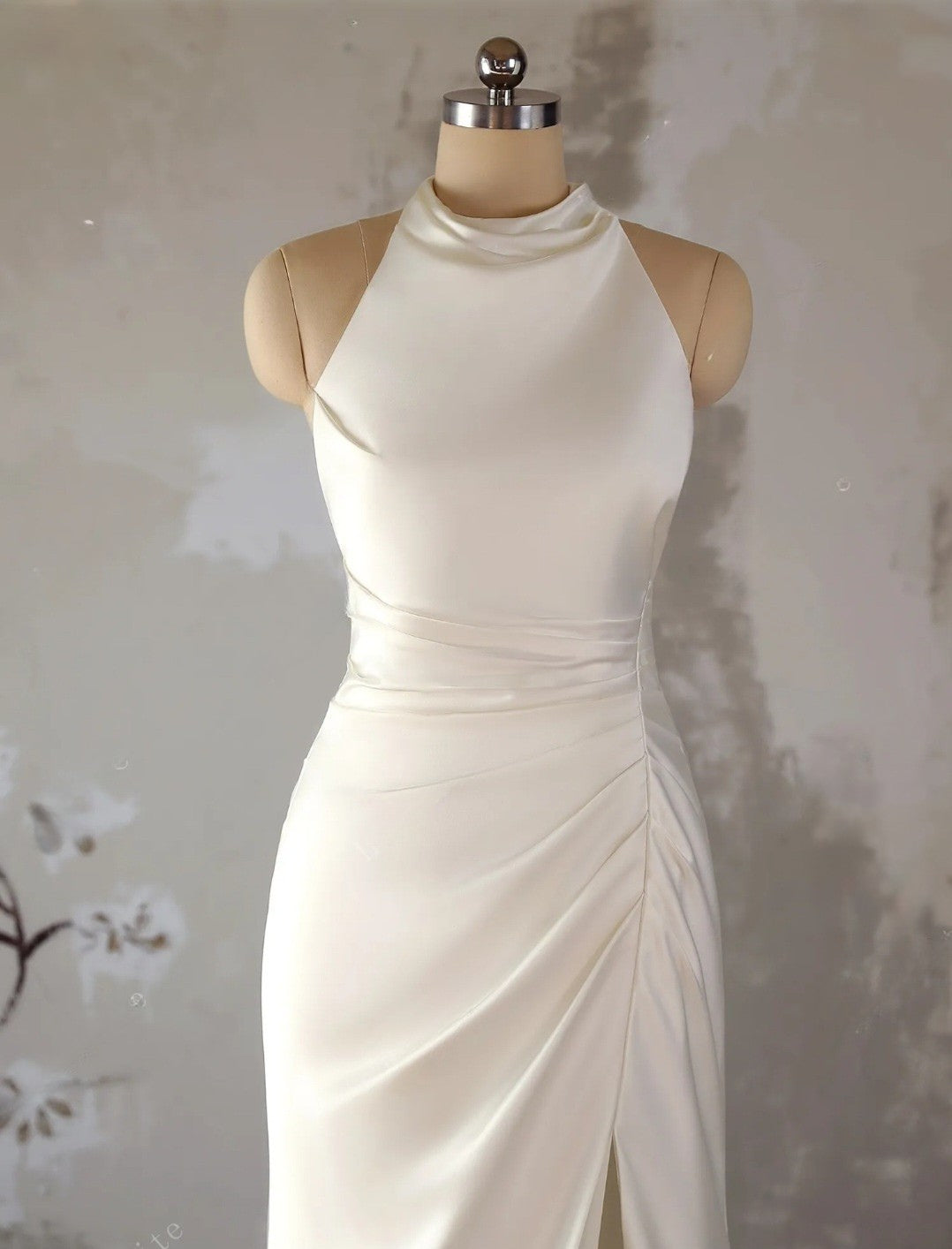 White evening gown on a mannequin against a neutral background