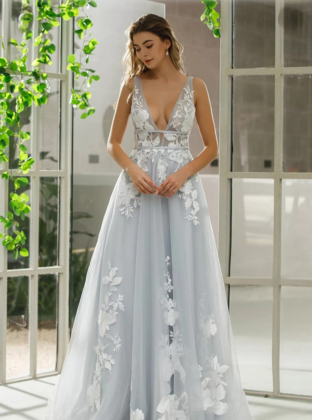 Woman wearing a light blue floral dress in a bright room with large windows.