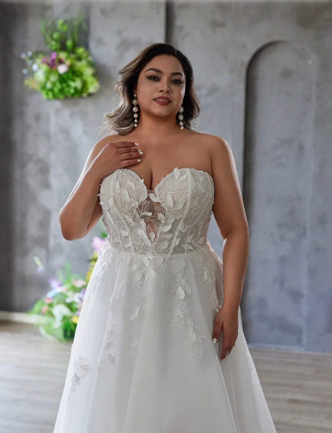 Woman wearing a white lace wedding dress in a decorated room with flowers.