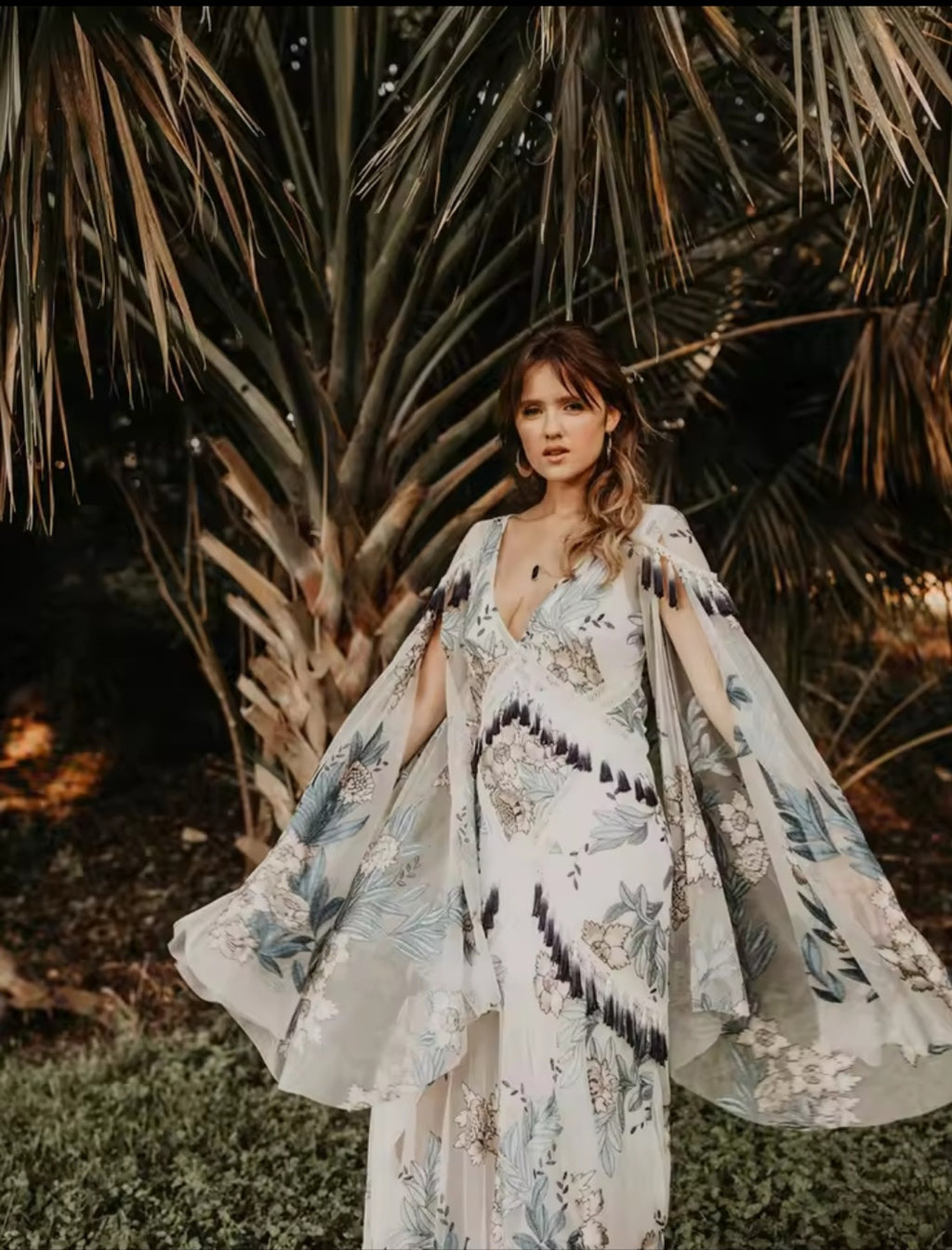 Woman in a floral dress standing in front of palm trees