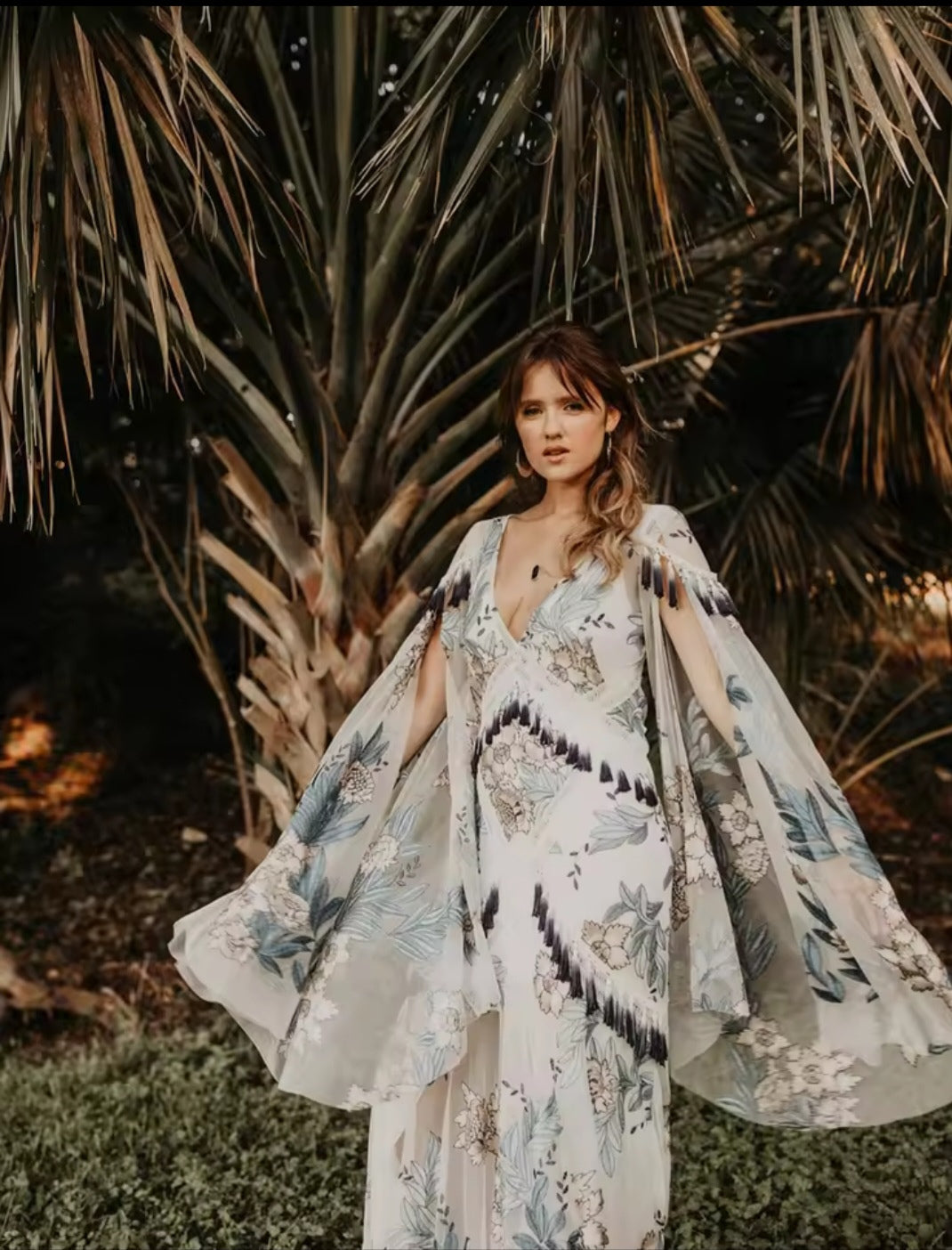 Woman in a floral dress standing in front of palm trees