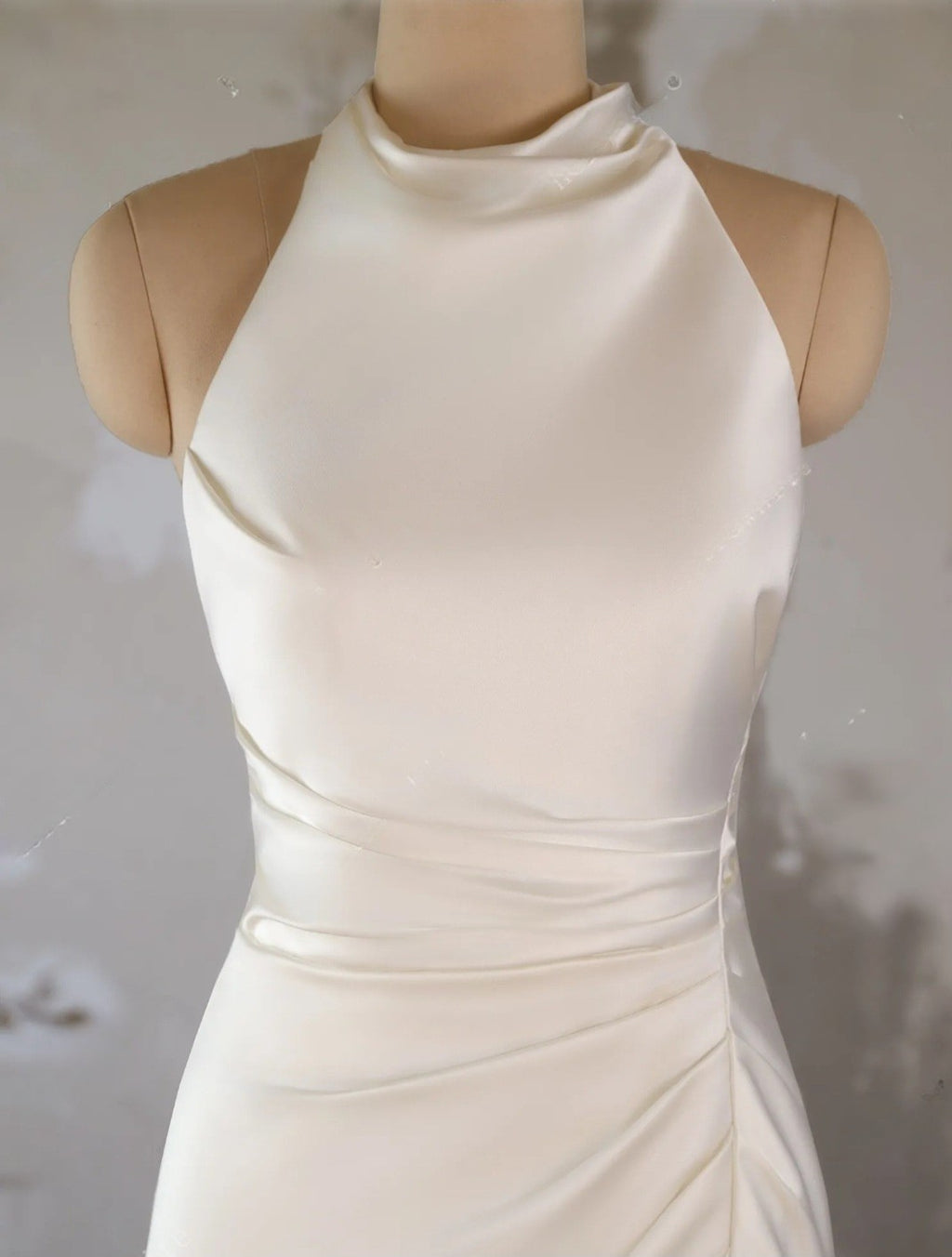 White halter neck dress on a mannequin against a plain background