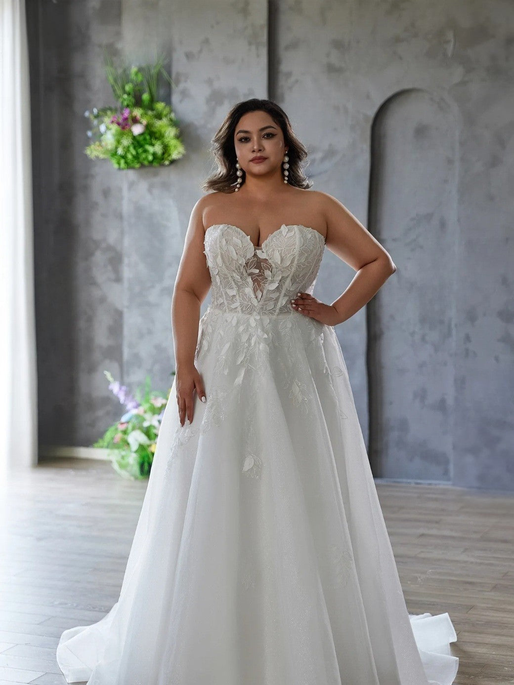 Woman in a white wedding dress standing indoors with a neutral background