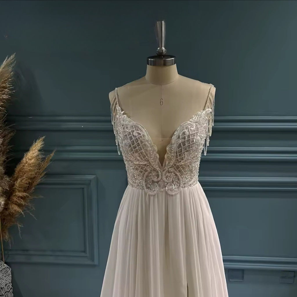 Elegant white lace dress on a mannequin against a dark blue wall.