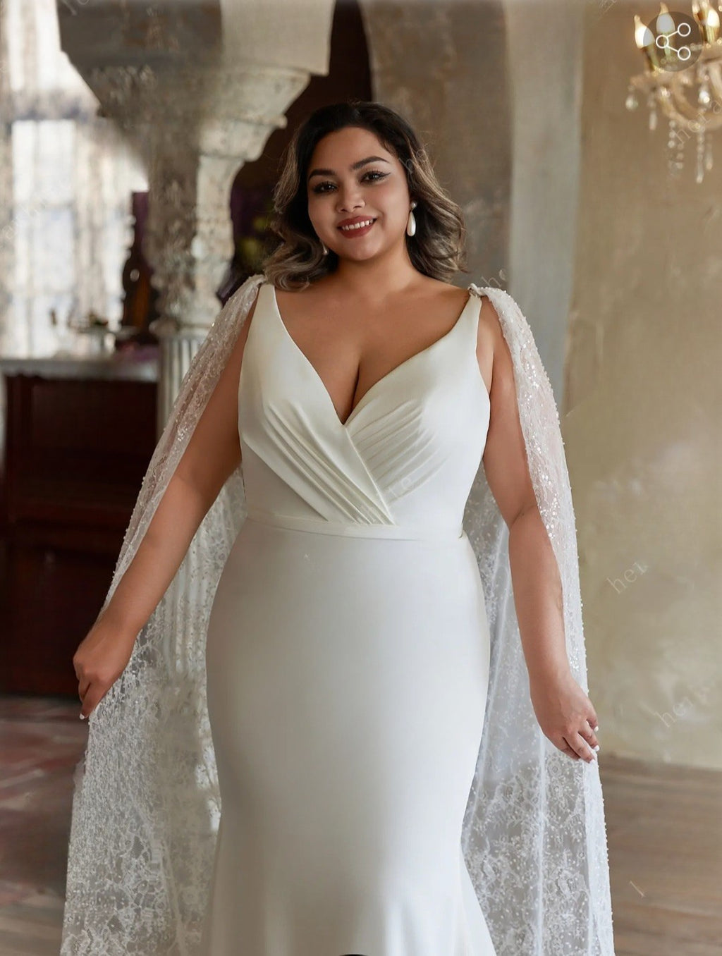 Woman wearing a white gown with a lace cape in an elegant indoor setting