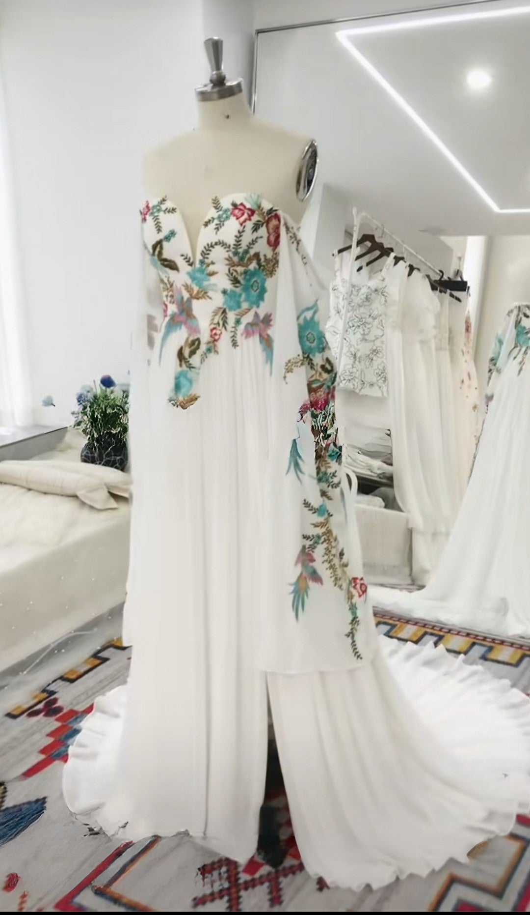 White dress with floral embroidery on a mannequin in a room setting.