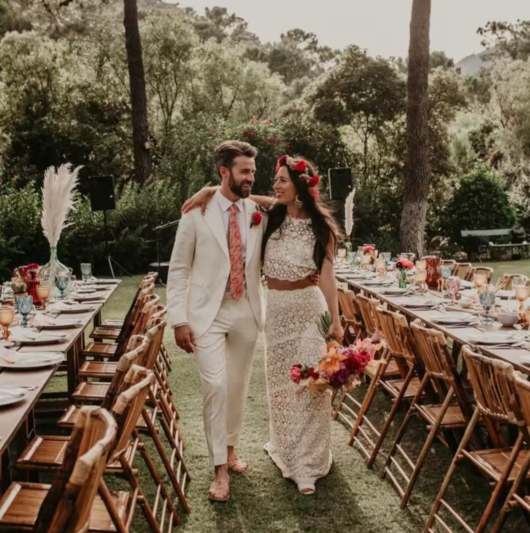 Couple walking through an outdoor wedding setup with tables and decorations.