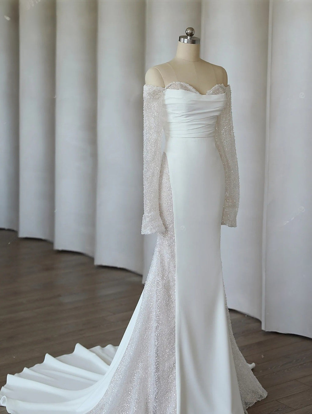 White lace wedding dress on a mannequin against a white curtain background