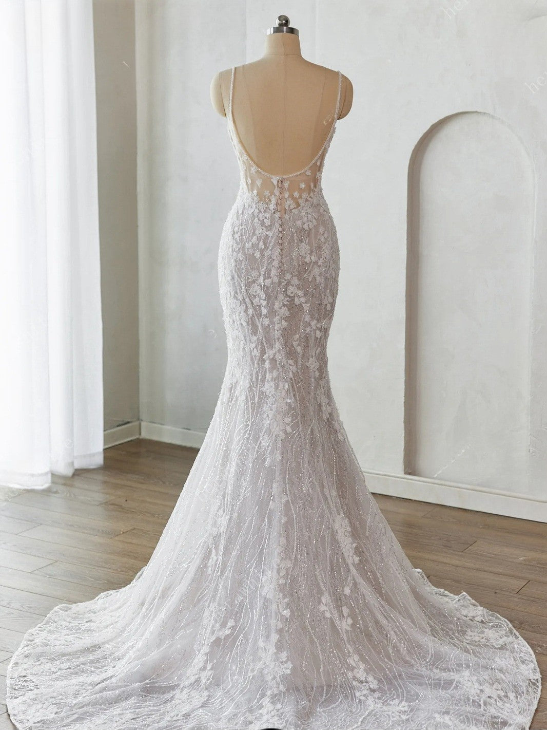 White lace wedding dress on a mannequin against a neutral background