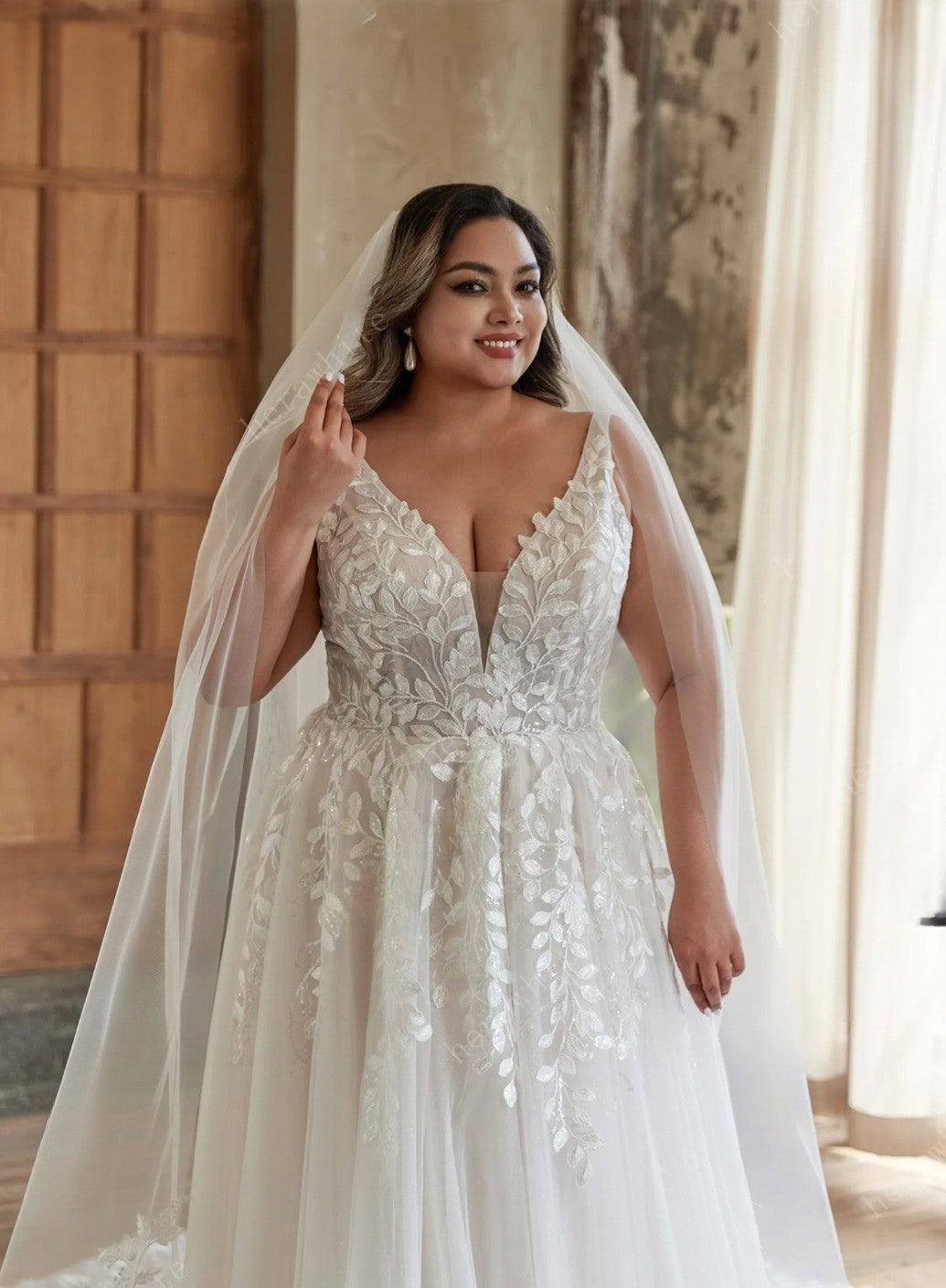 Woman wearing a white wedding dress with a veil indoors.