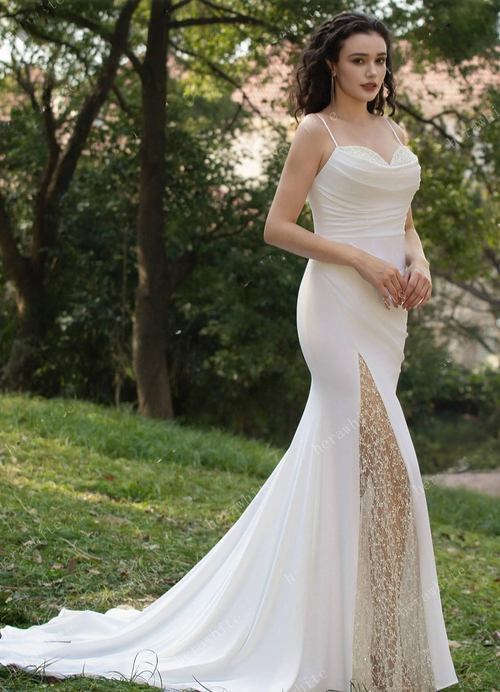 Woman in a white wedding dress with a gold slit standing outdoors.