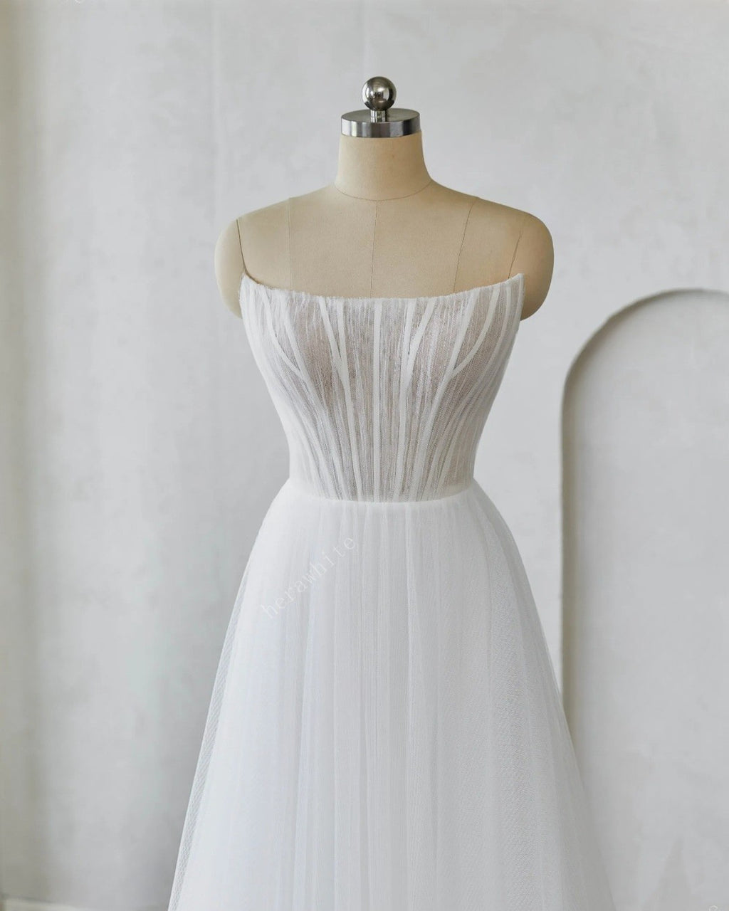 White strapless dress on a mannequin against a plain background