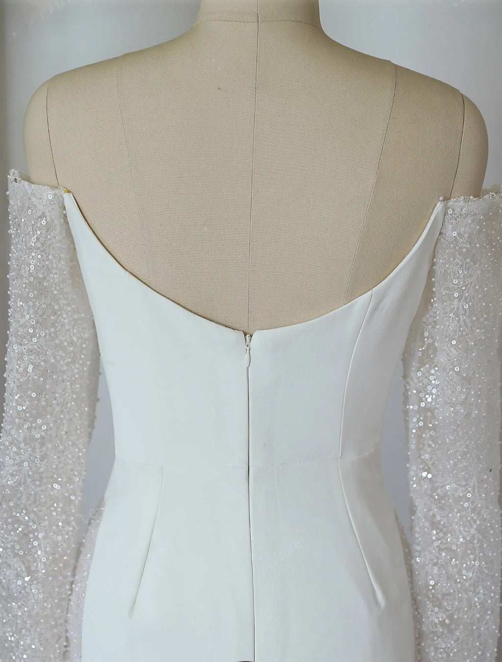 White evening gown with sheer sleeves on a mannequin against a white background