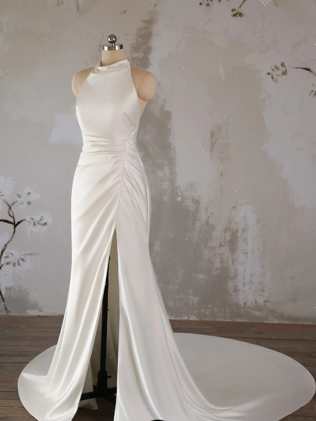 White evening gown on a mannequin against a textured wall.