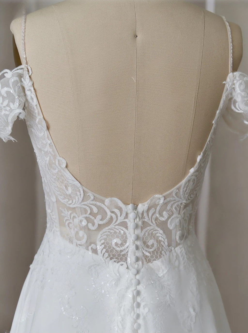 White lace wedding dress on a mannequin with a neutral background