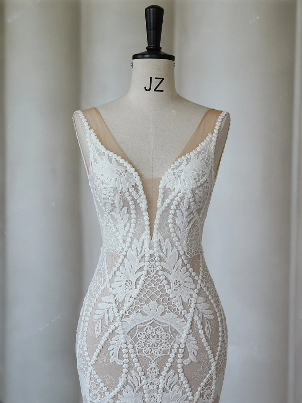 White lace dress on a mannequin with with a plain background