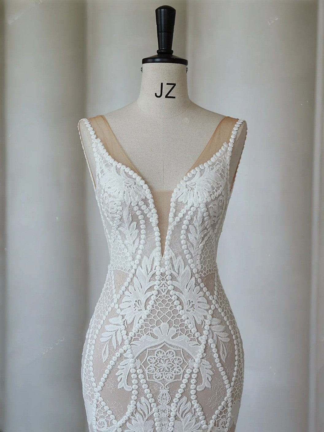 White lace dress on a mannequin with with a plain background