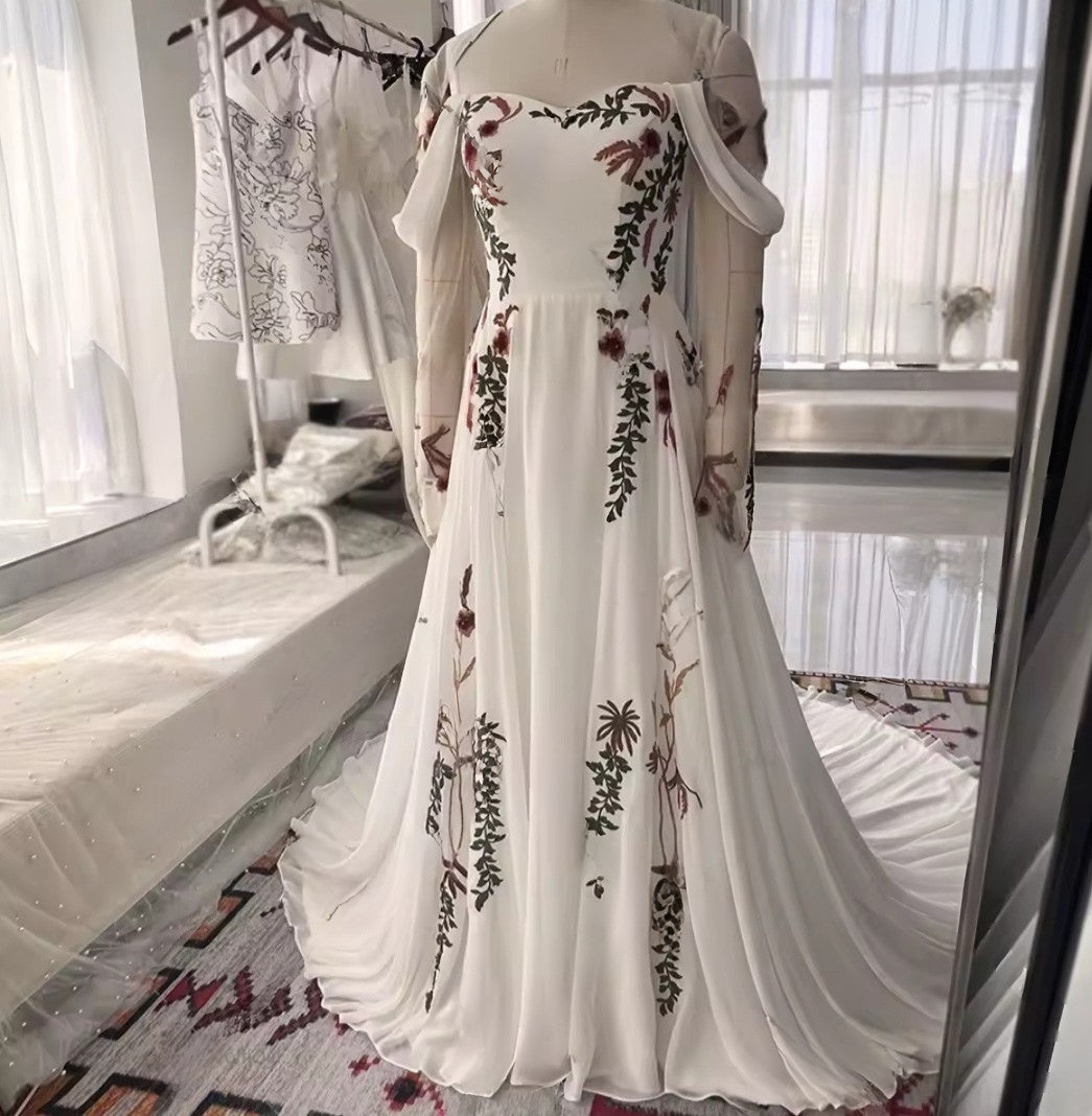 White off-shoulder dress with floral embroidery on a mannequin in a room.