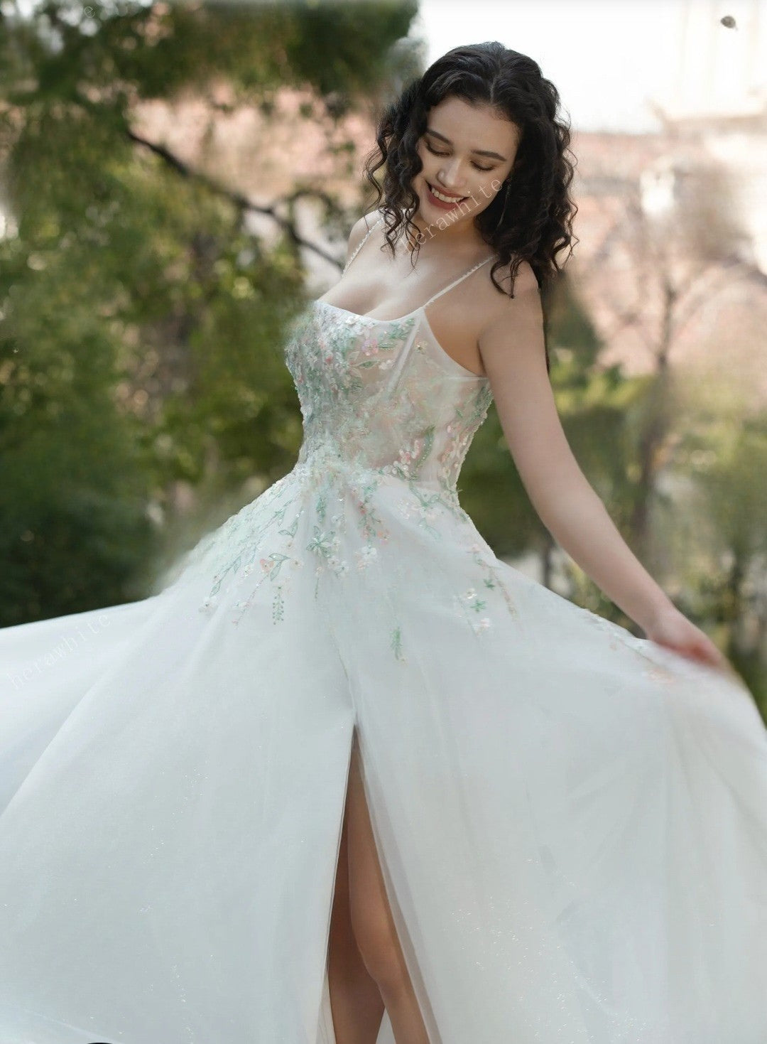 Woman in a white floral dress standing outdoors with greenery in the background