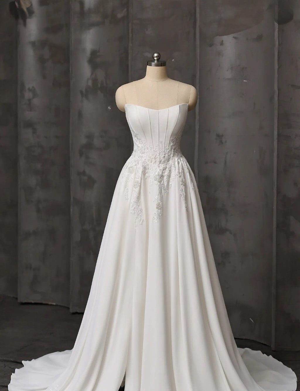 White strapless wedding dress on a mannequin against a dark background