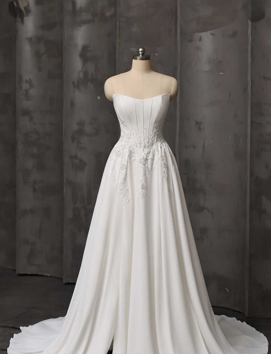 White strapless wedding dress on a mannequin against a dark background