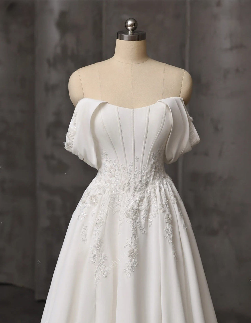 White off-shoulder dress on a mannequin against a dark background