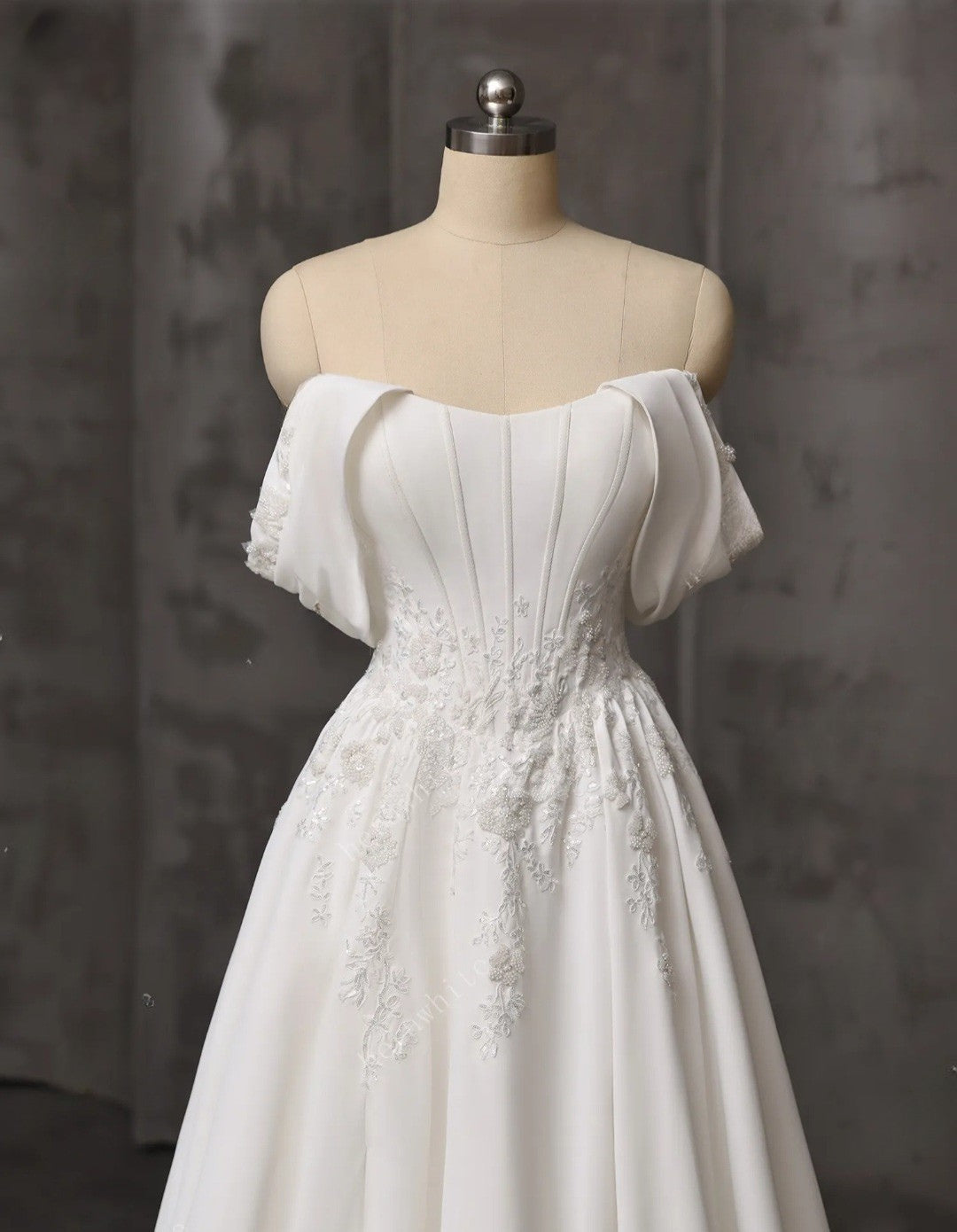 White off-shoulder dress on a mannequin against a dark background