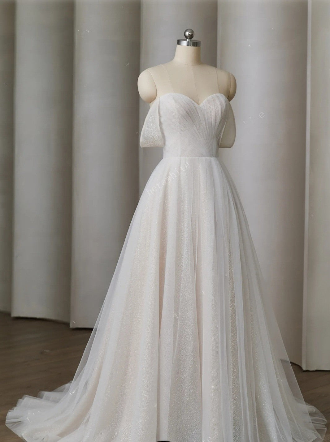 White wedding dress on a mannequin against a plain background