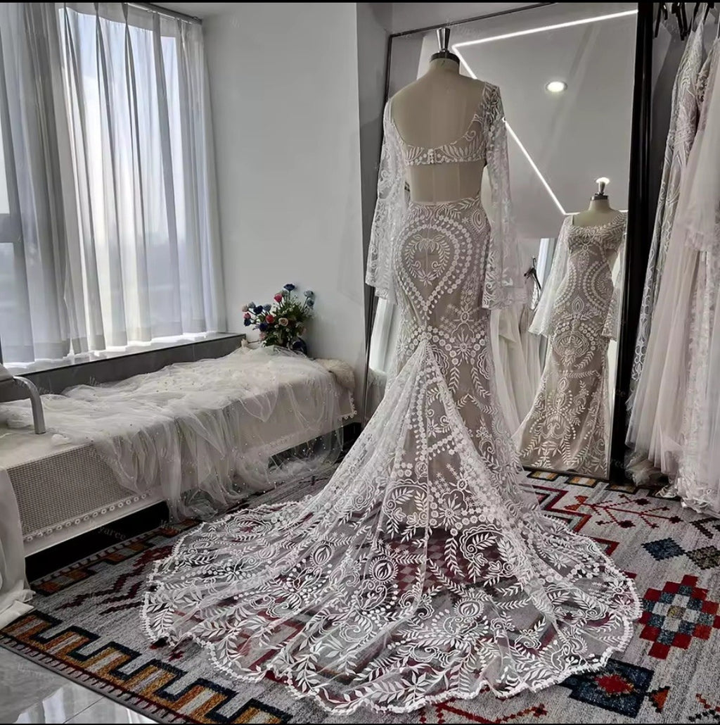 Lace wedding dress on a mannequin in a room with a bed and window.
