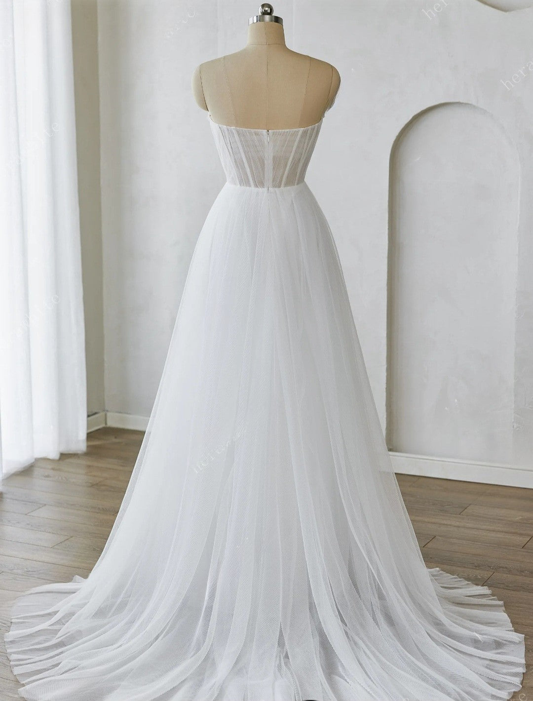 White wedding dress on a mannequin against a white wall.