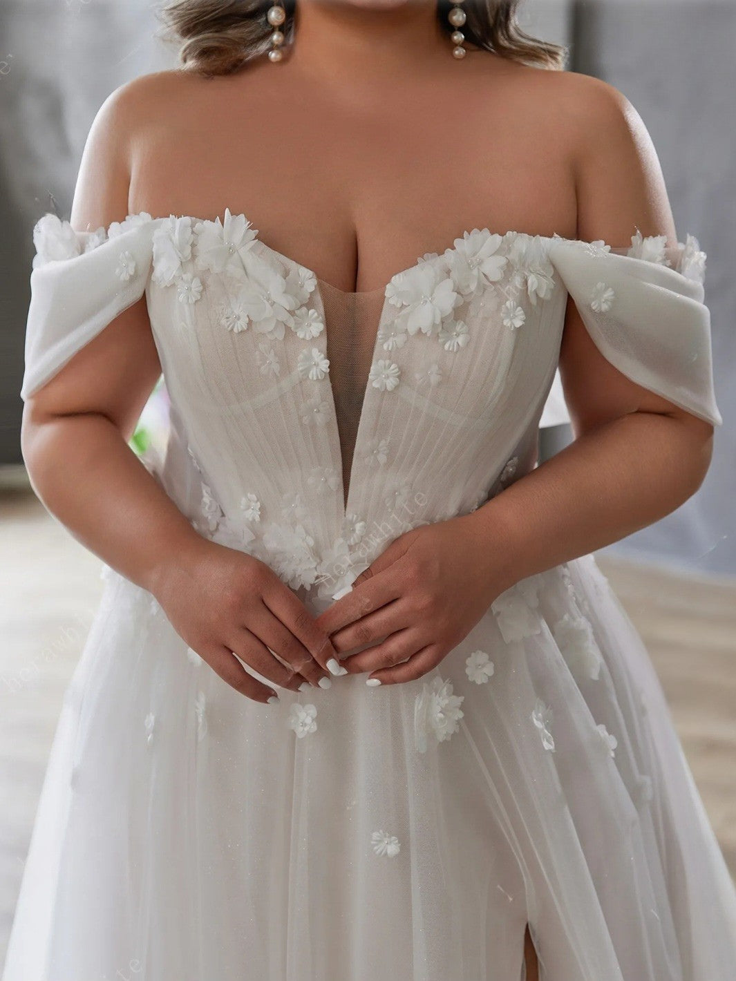 White off-shoulder wedding dress with floral details on a neutral background