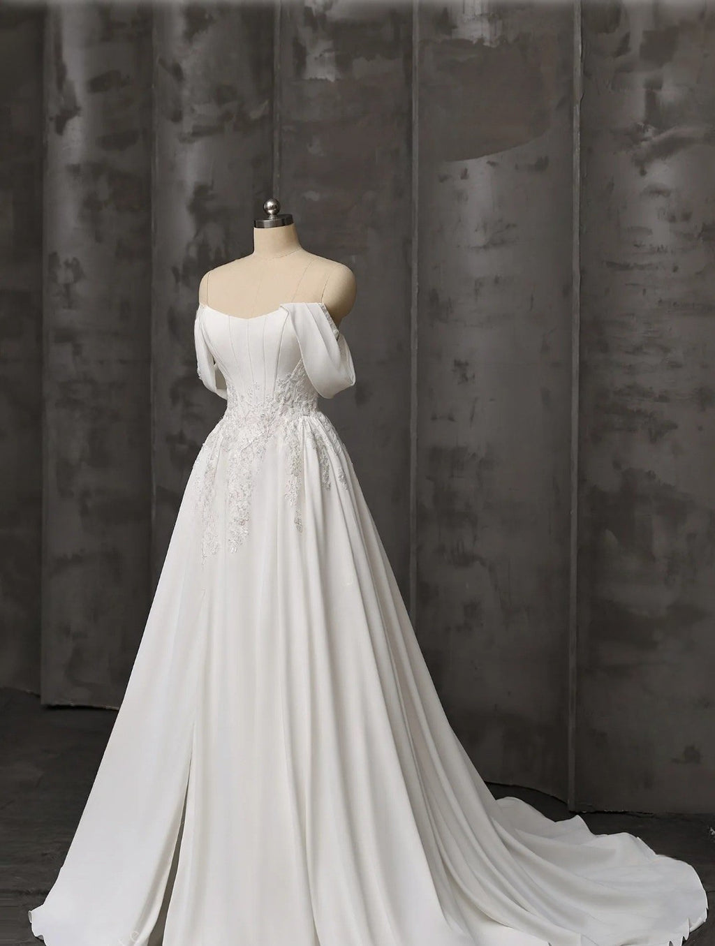 White wedding dress on a mannequin against a dark curtain background