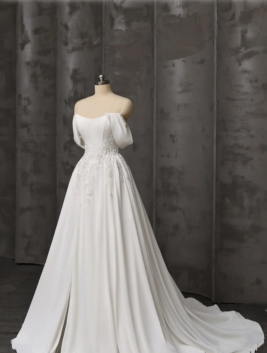 White wedding dress on a mannequin against a dark curtain background