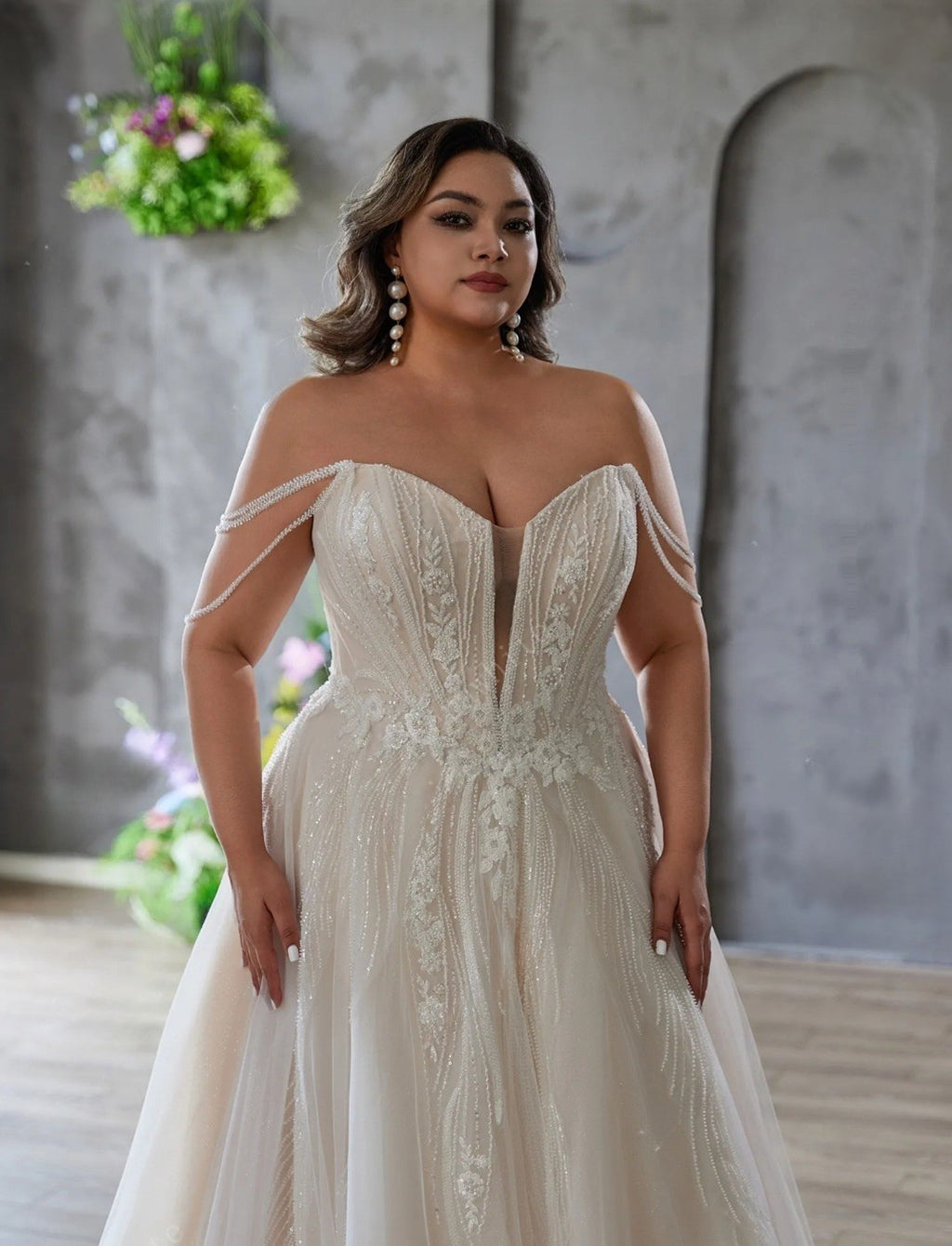 Woman wearing a white wedding dress with floral decorations in the background