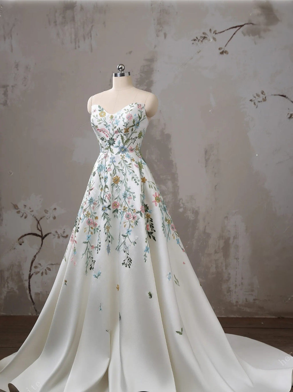 Floral dress on a mannequin against a floral-patterned wall.