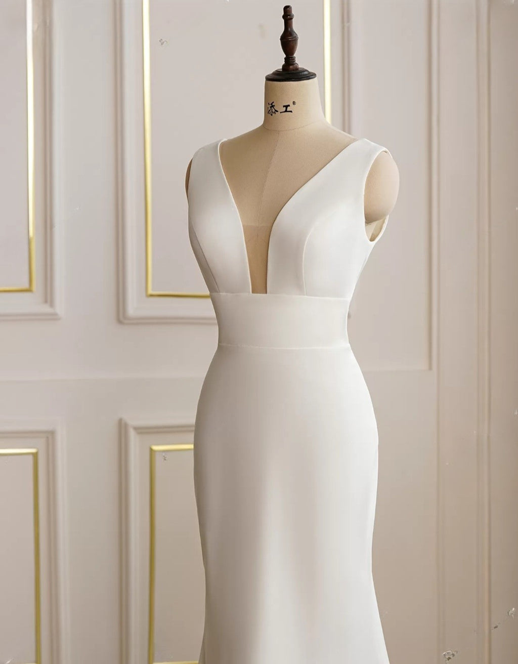 White evening gown on a mannequin against a white wall with gold trim