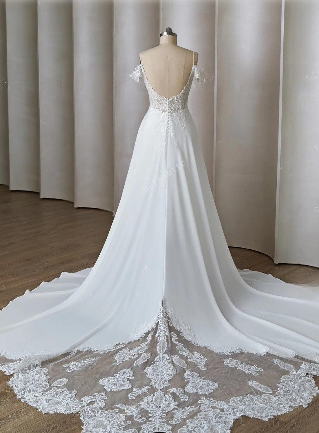 White wedding dress with lace details on a mannequin against a neutral background