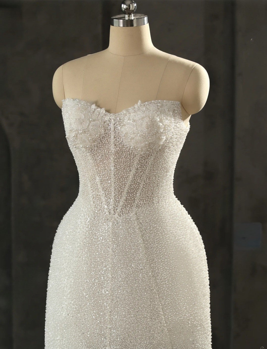 White beaded dress on a mannequin against a dark background